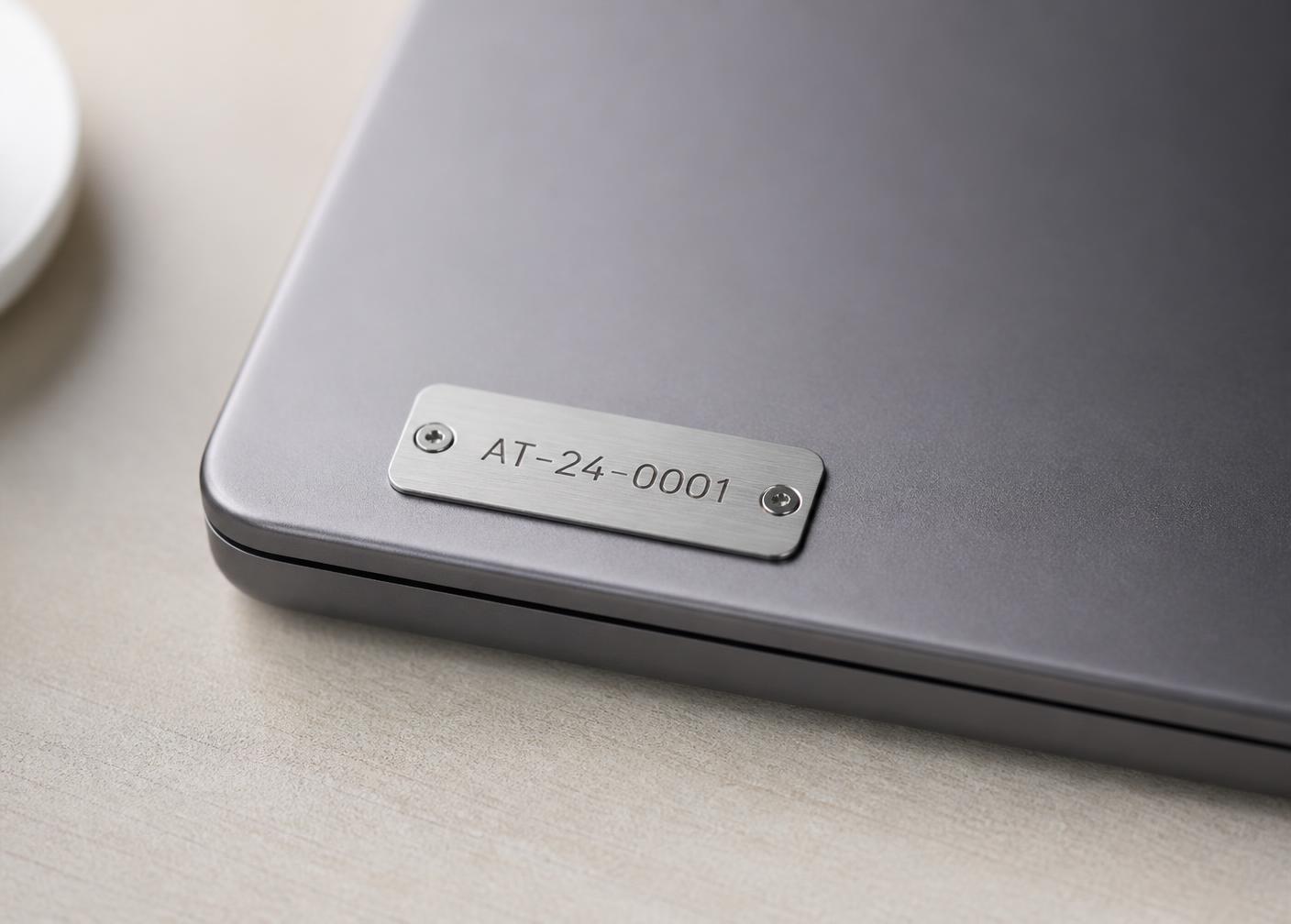 Aluminium asset tag with engraved serial number fixed to a laptop lid